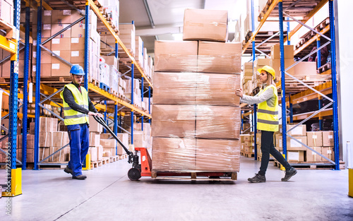 Cuadros en Lienzo Warehouse workers pulling a pallet truck.
