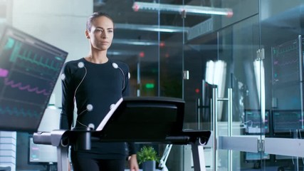 Wall Mural - beautiful woman athlete with electrodes connected to her body walks on a treadmill in a sports scien