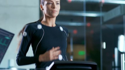 Wall Mural - beautiful woman athlete with electrodes connected to her body runs on a treadmill in a sport science