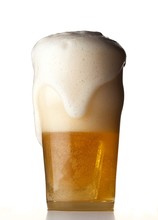 Froth Overflowing Glass Of Beer On White Background
