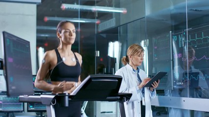 Wall Mural - beautiful woman athlete runs on a treadmill with electrodes attached to her body, female physician u