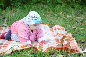 happy little cute newborn baby boy sitting on a green meadow in the grass on the nature in the park. autumn or sprimg day