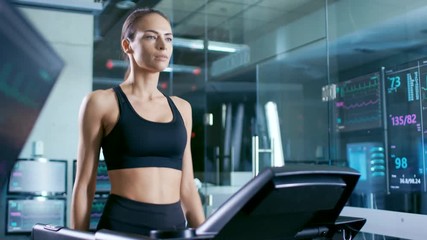 Wall Mural - beautiful woman athlete wearing sport bra, walks on a treadmill in a sports science laboratory. in t