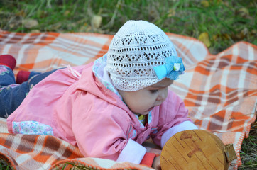 happy little cute newborn baby boy sitting on a green meadow in the grass on the nature in the park. autumn or sprimg day