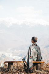 Poster - Woman resting on a bench in front of mountains.