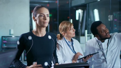 Wall Mural - beautiful woman athlete runs on a treadmill with electrodes attached to her body, while two scientis