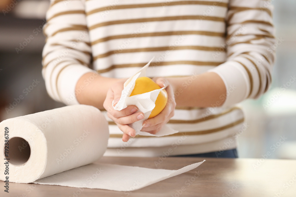 Woman wiping apple with paper towel in kitchen