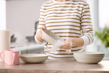 Woman Wiping Dishware With Paper Towel In Kitchen