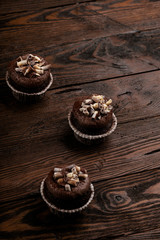 Wall Mural - chocolate cupcakes on a brown wooden background decorated with chocolate shaving