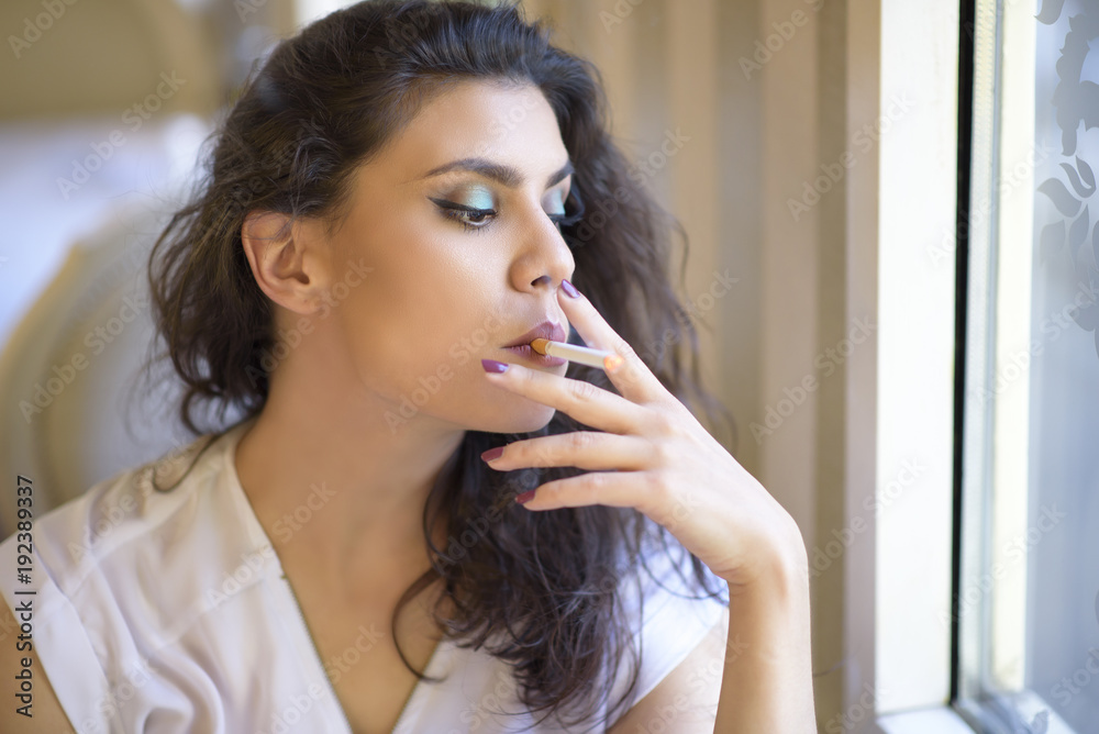 inhaling cigarette smoke Beautiful young woman inhaling a smoke from a cigarette, enjoying her habit  inside a coffee shop Stock Photo