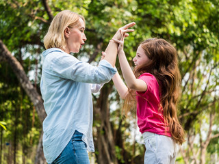 Wall Mural - Mother and daughter having fun together in a park. Family and lifestyle concept