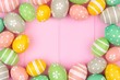Pastel color Easter egg frame against a pink wood background. Top view with copy space.