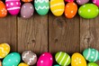 Colorful Easter double border against a rustic old wood background. Top view with copy space.