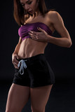 cropped close up body of fit woman wearing shorts and sport top showing  slim beautiful stomach and abs in diet fitness and healthy lifestyle  concept isolated on black background Stock Photo