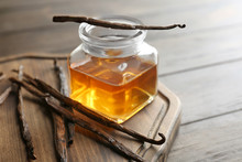 Jar With Vanilla Extract And Sticks On Wooden Board