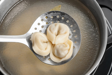 Wall Mural - Cooked dumplings on skimmer over saucepan