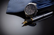 Father's Day or business concept image. Elegant man's watch, fountain pen and blue tie on black gradient background.
