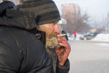 Homeless Man Smoking On The Bench In Winter