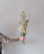 © Anna Cor - Woman's hand holding bouquet of flowers against gray wall