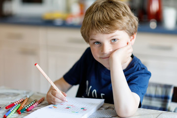 Wall Mural - Happy smiling kid boy at home making homework writing letters with colorful pens