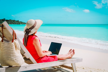 Wall Mural - remote work concept -young woman with laptop on beach