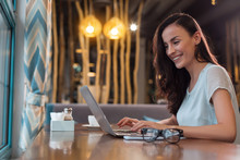 Work Everywhere. Attractive Beautiful Female Freelancer Typing While Looking At Screen And Smiling