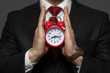 Wall Mural - Time concept - handsome businessman in formal suit holding red clock