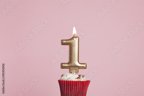 Fotografía Number 1 gold candle in a cupcake against a pastel pink background