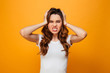 © Drobot Dean - Displeased serious brunette woman in t-shirt holding her head
