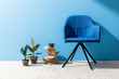 © LIGHTFIELD STUDIOS - cozy chair with books and ficus pots in front of blue wall