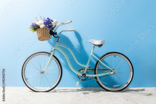 Dekoracja na wymiar  widok-z-boku-roweru-z-kwiatami-w-koszu-przed-niebieska-sciana