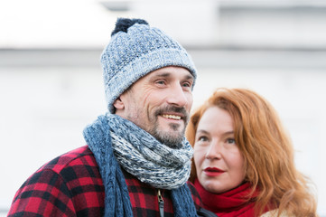 Smiling guy and rude women. Lovely aged couple in city. Styled aged pair likes winter. Woman in red scarf looks at smiling men.