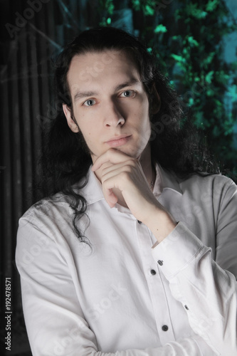 Handsome Manly Guy With Long Black Hair Stands In White Shirt On