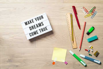 Wall Mural - make your dreams come true written on lightbox in office as flatlay