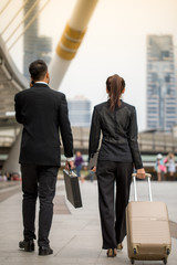 Asia Businessmen and businesswoman are walking on a street in The city. Young business traveler pulling suitcase