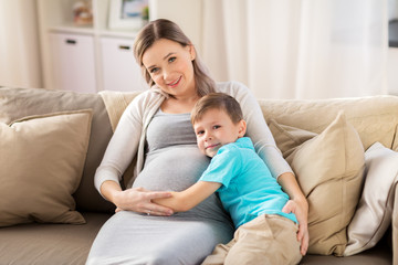 Poster - happy pregnant mother and son hugging at home