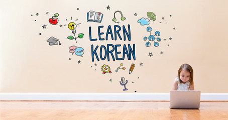 Wall Mural - Learn Korean text with little girl using a laptop computer on floor