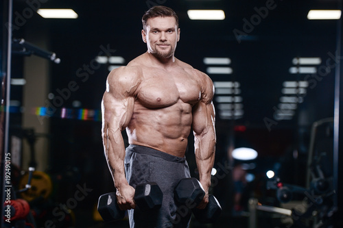 Cuadros en Lienzo Brutal strong bodybuilder athletic men pumping up muscles with dumbbells
