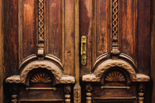 Vintage Background. Elements Of An Old Carved Wooden Door Decorated With Voluminous Carved Wooden Elements Imitating The Weaving. A Vintage Concept Of Old Antiques. Varnished Old Mahogany