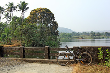 Bicycle parked while off road biking along picturesque countryside with lakes and lagoons in Kerala, India