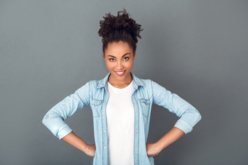 Young african woman isolated on grey wall studio casual daily lifestyle hands on waist