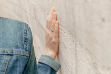 White Woman Hand Touches The Wall. Closeup Of Religion Fingers On The Stone Ancient Street Wall.