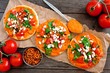 Spicy hummus mini flat breads with tomatoes and feta. Above scene with on a rustic wood background. Healthy eating concept.