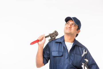 Indian plumber at work with Pipe wrench or plumbing spanner, standing isolated over white background
