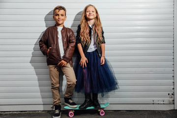 Portrait of two teenage school children on a garage door background in a city park street.