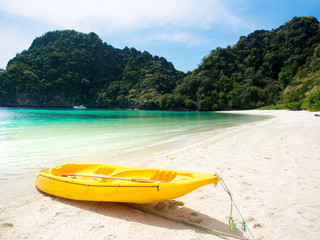 Wall Mural - Yellow kayak boat on white sand beach at the sea with mountains view background for summer holiday concept.