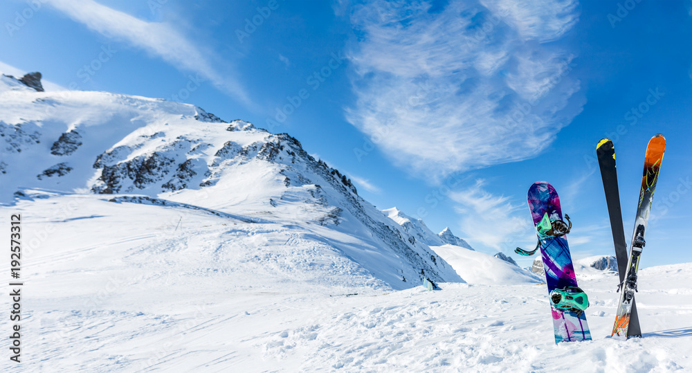 Photo of crossed skis and sticks against background of snowy landscape - obrazy, fototapety, plakaty 