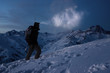 Extreme tourism. Brave expeditor lights the way with a headlamp at night winter mountains. Man with backpack commit climb on snowy slope in high ridge. Ski tour