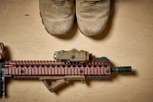 Fotografia Top view of used military boots and rifle on a wooden background