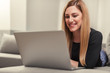© Denis Rozhnovsky - Attractive woman using a laptop while lying on the couch at home.